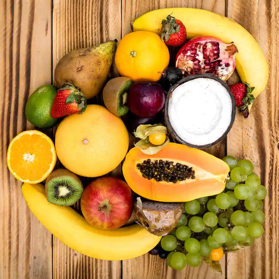 An assortment of fresh tropical and seasonal fruits arranged on a wooden surface.