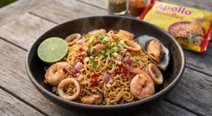 Steaming close-up of a rustic bowl of authentic Mauritian spicy seafood noodles (prawns, squid, mussels), with a yellow packet of Apollo Noodles UK visible on a wooden table in the background.